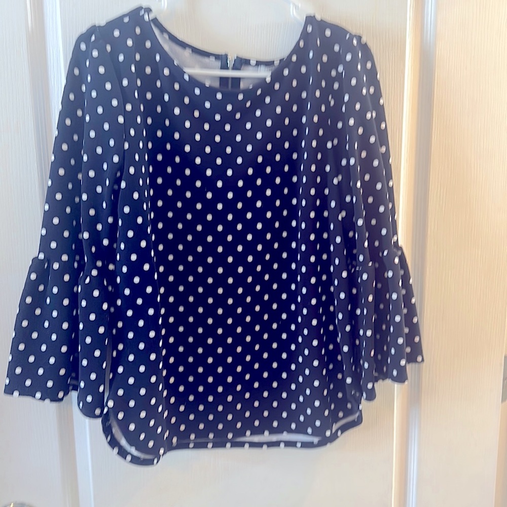 Blue form fitting top with white polka dots, zipper detail in back,flowy sleeves
